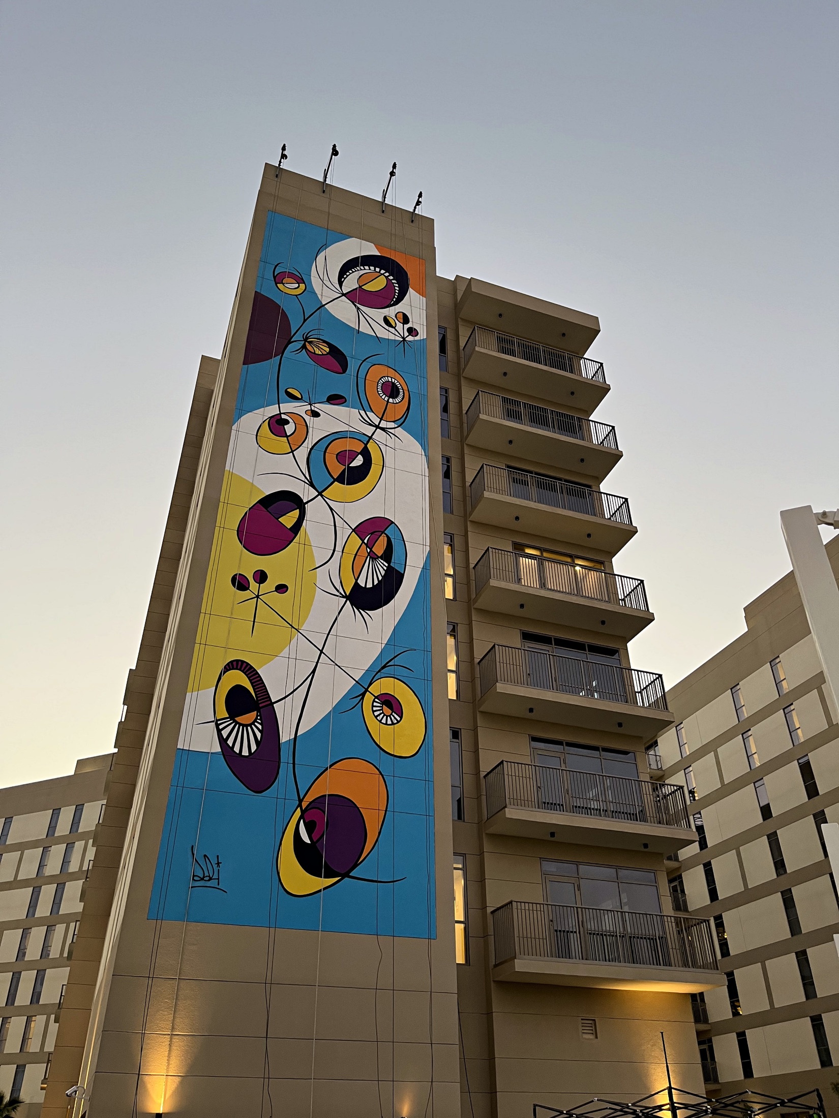 Dozi Dreams’ completed circular blue, yellow and purple mural at dusk