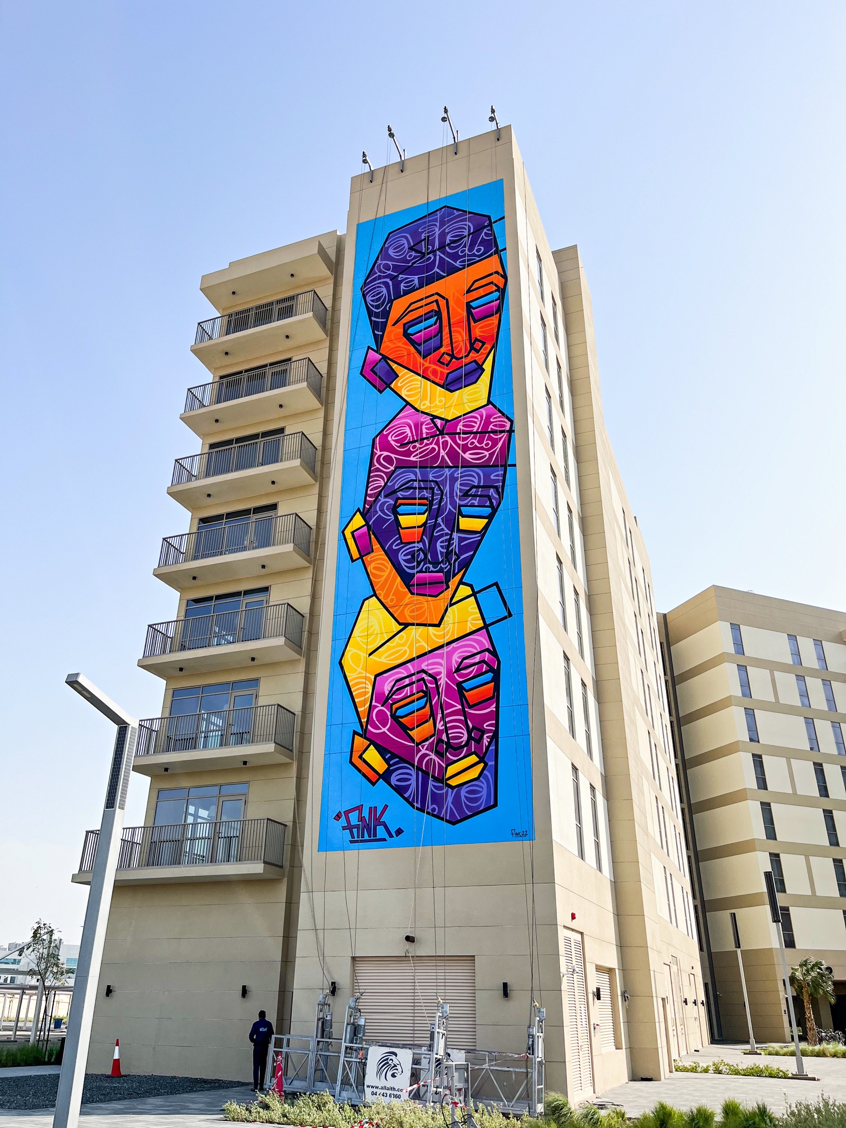Fink.22’s completed mural of three colourful faces across a full-height Aldar facade