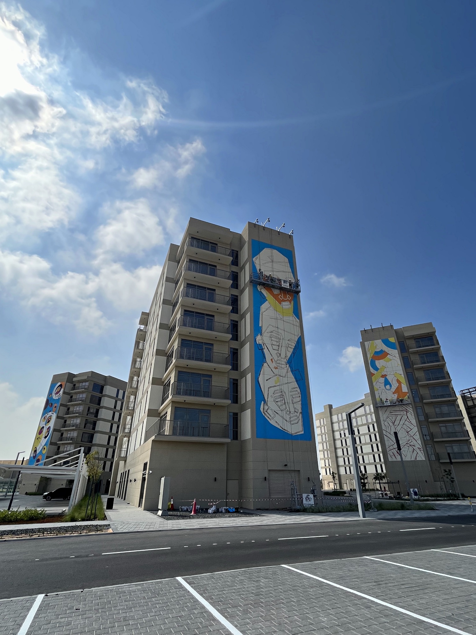 Three Aldar buildings at different stages of the coordinated mural programme