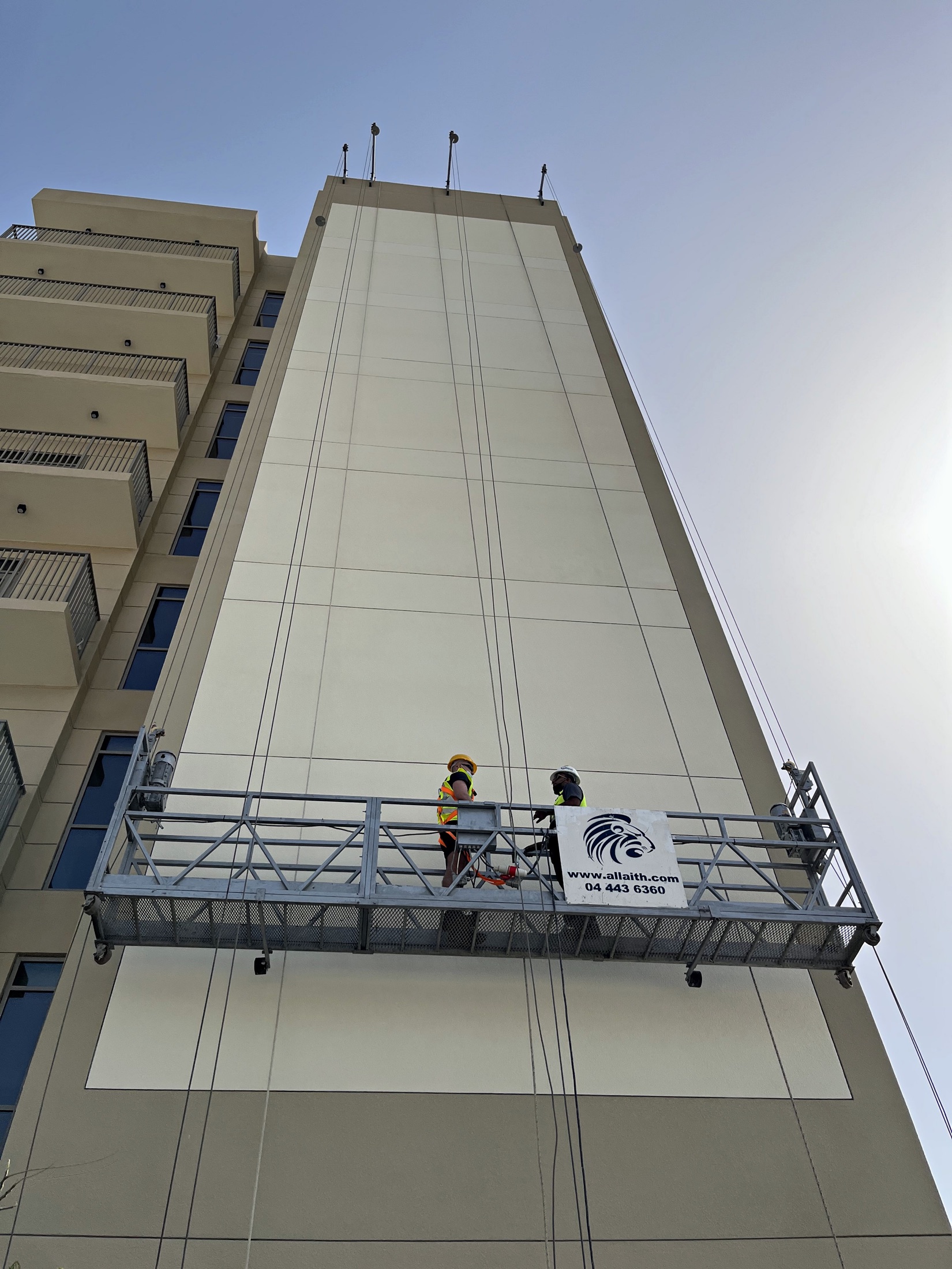 Suspended cradle and specialist crew below a 26-metre Aldar mural surface