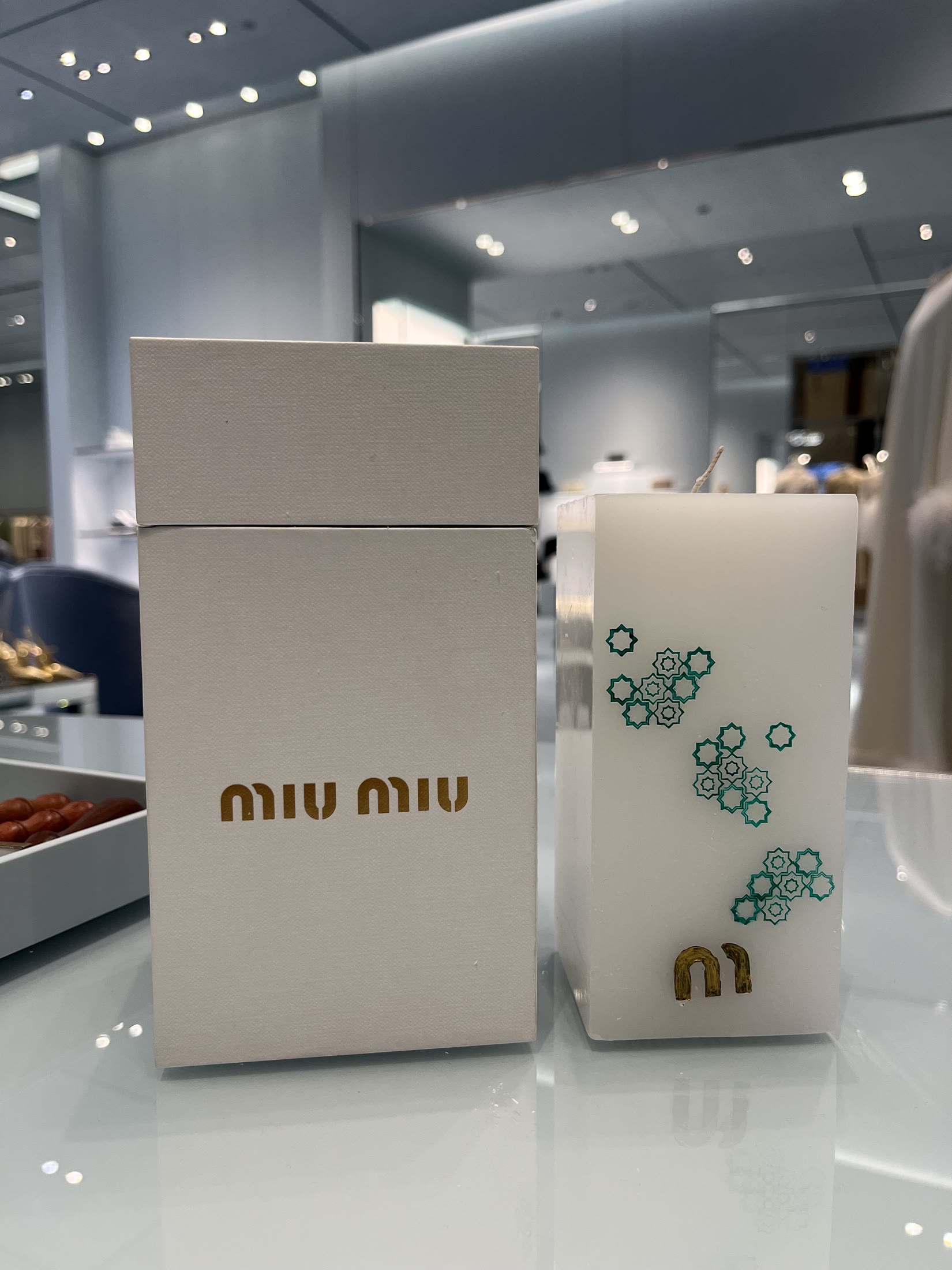Hand-painted Miu Miu candle beside its finished packaging