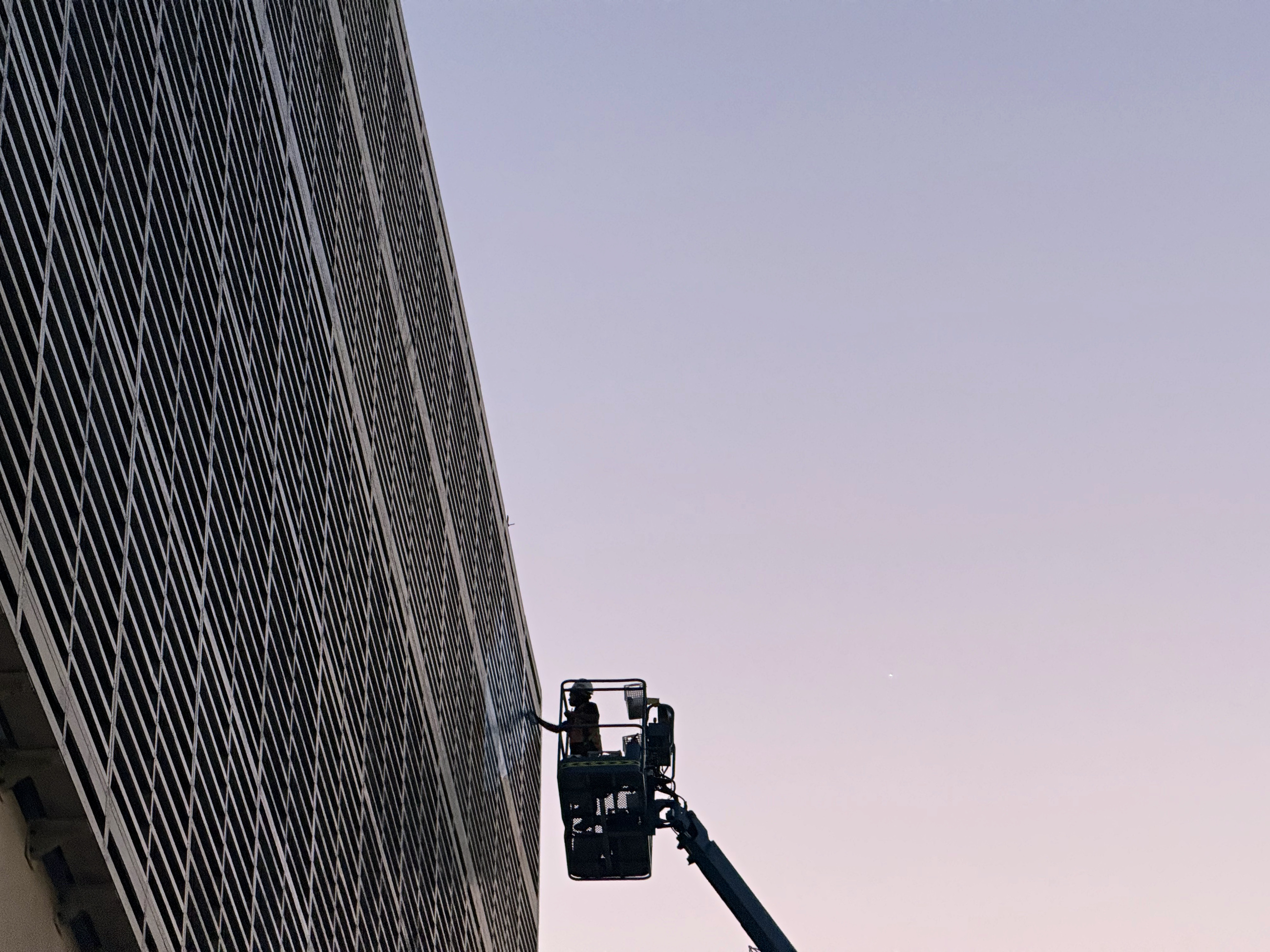 The painted Tabreed louvre elevation and specialist access equipment at dusk