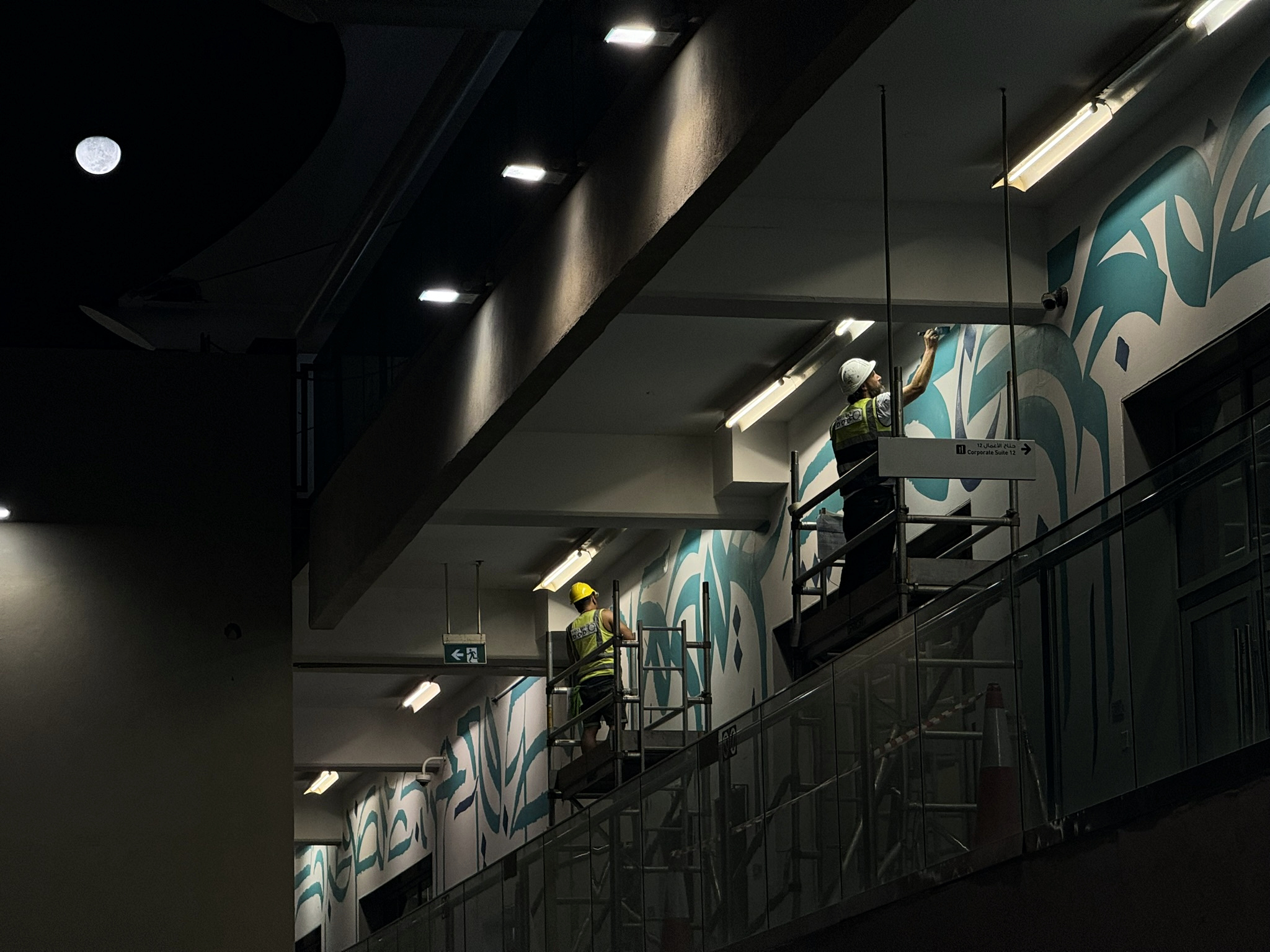 Specialist mural crew working at night across the Paddock Club elevation