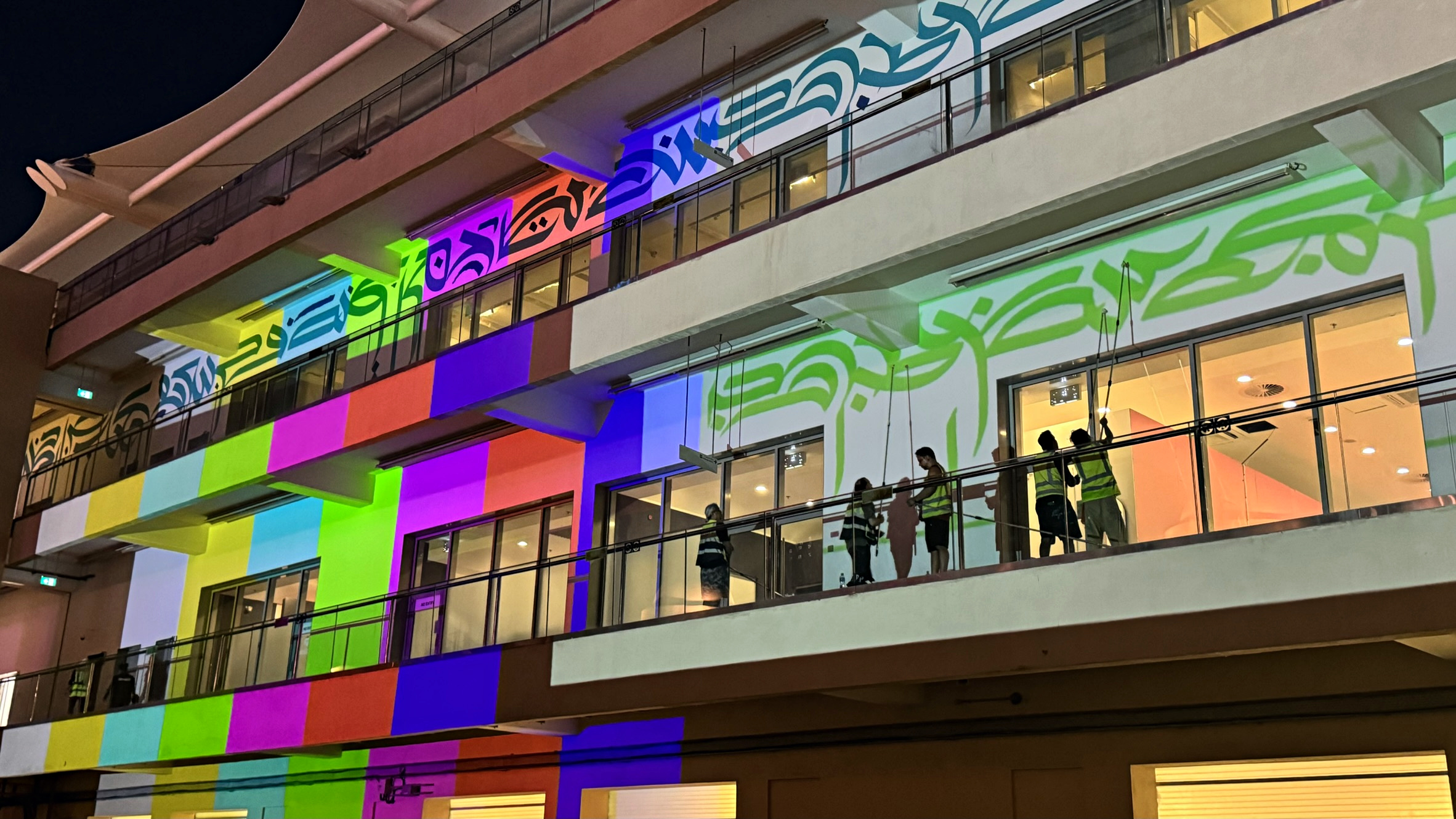 Gallery Dod team working across a multicoloured Paddock Club elevation at night