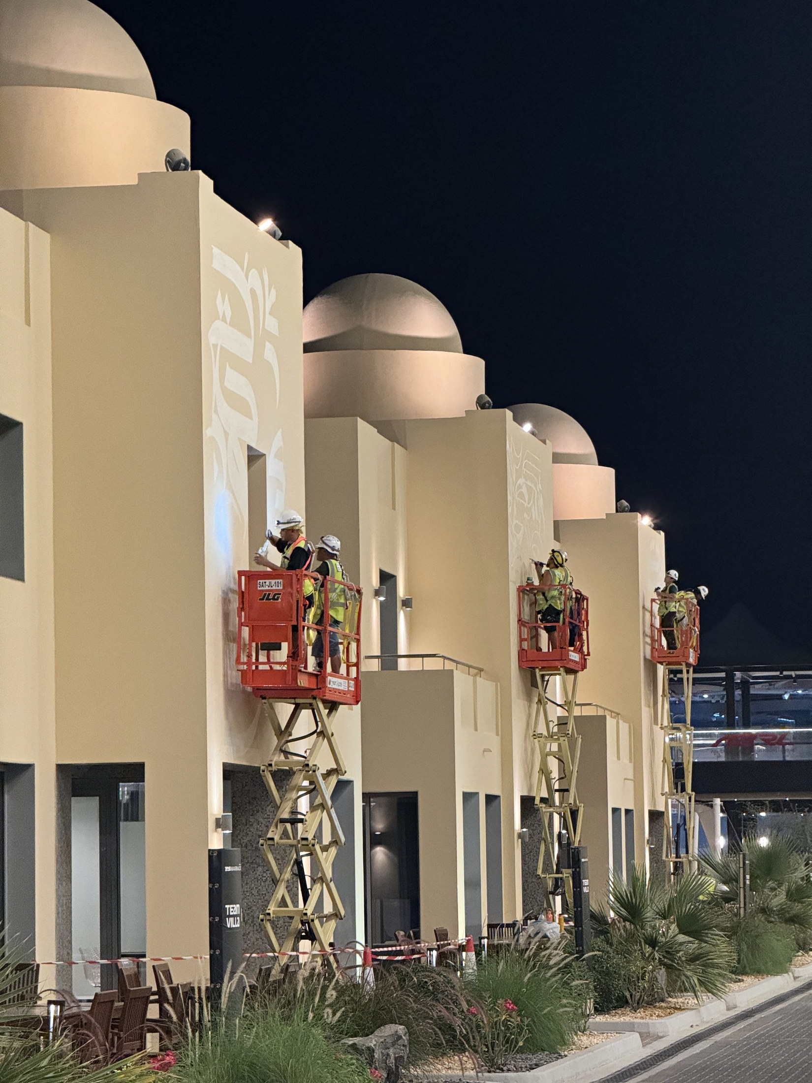 Artists painting the Team Villas from elevated platforms