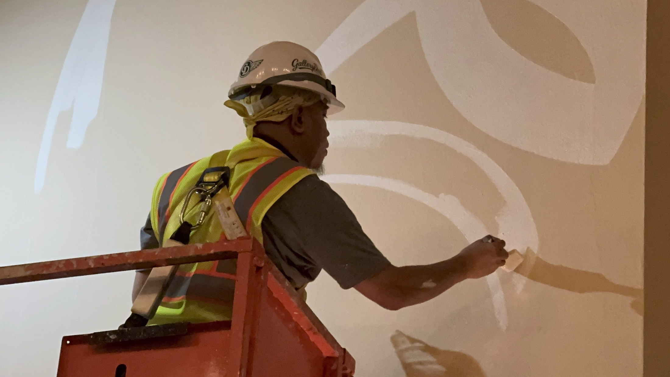 Artist hand painting the mural from a lift
