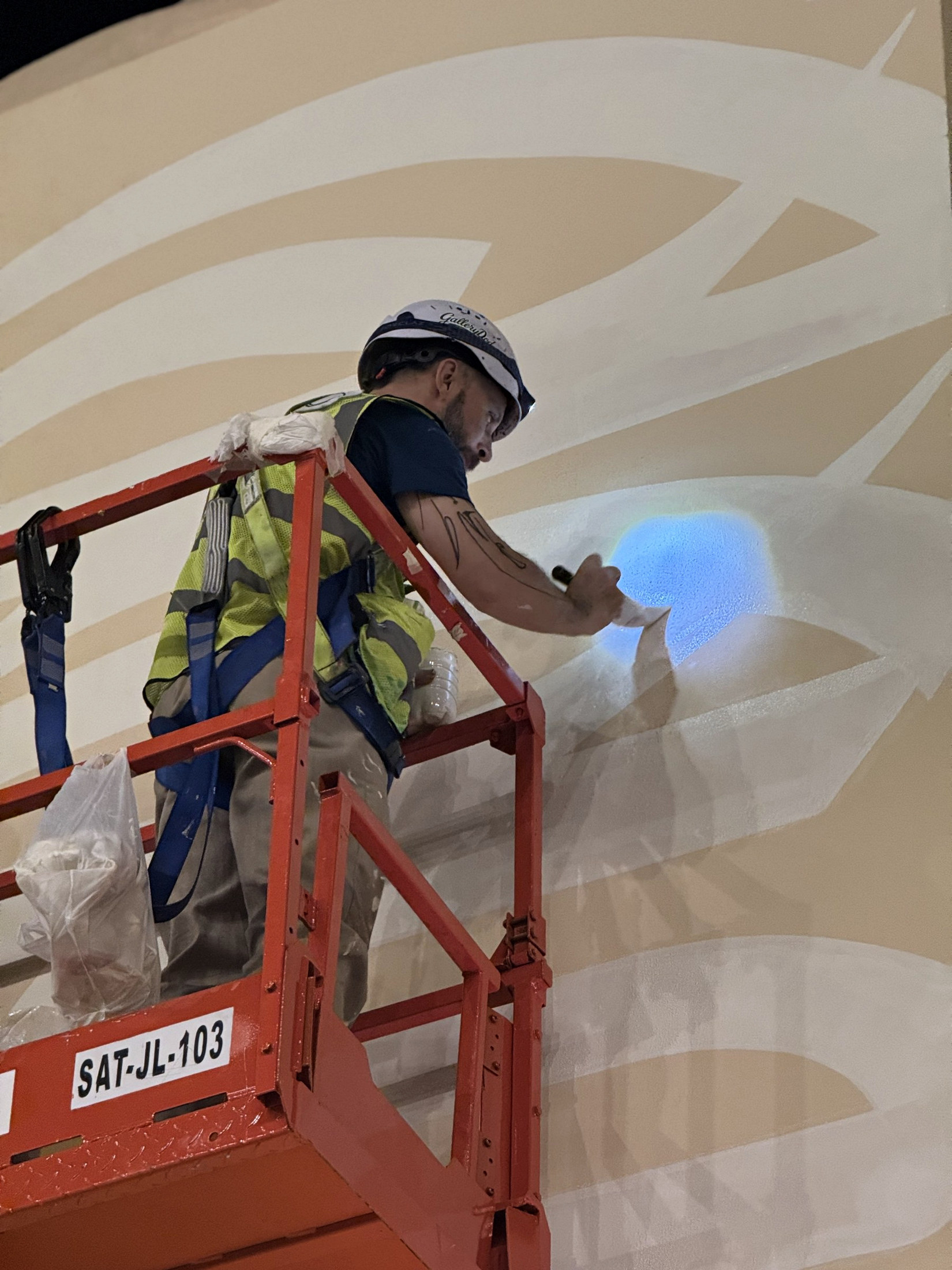 Artist rolling paint onto a large Team Villa mural