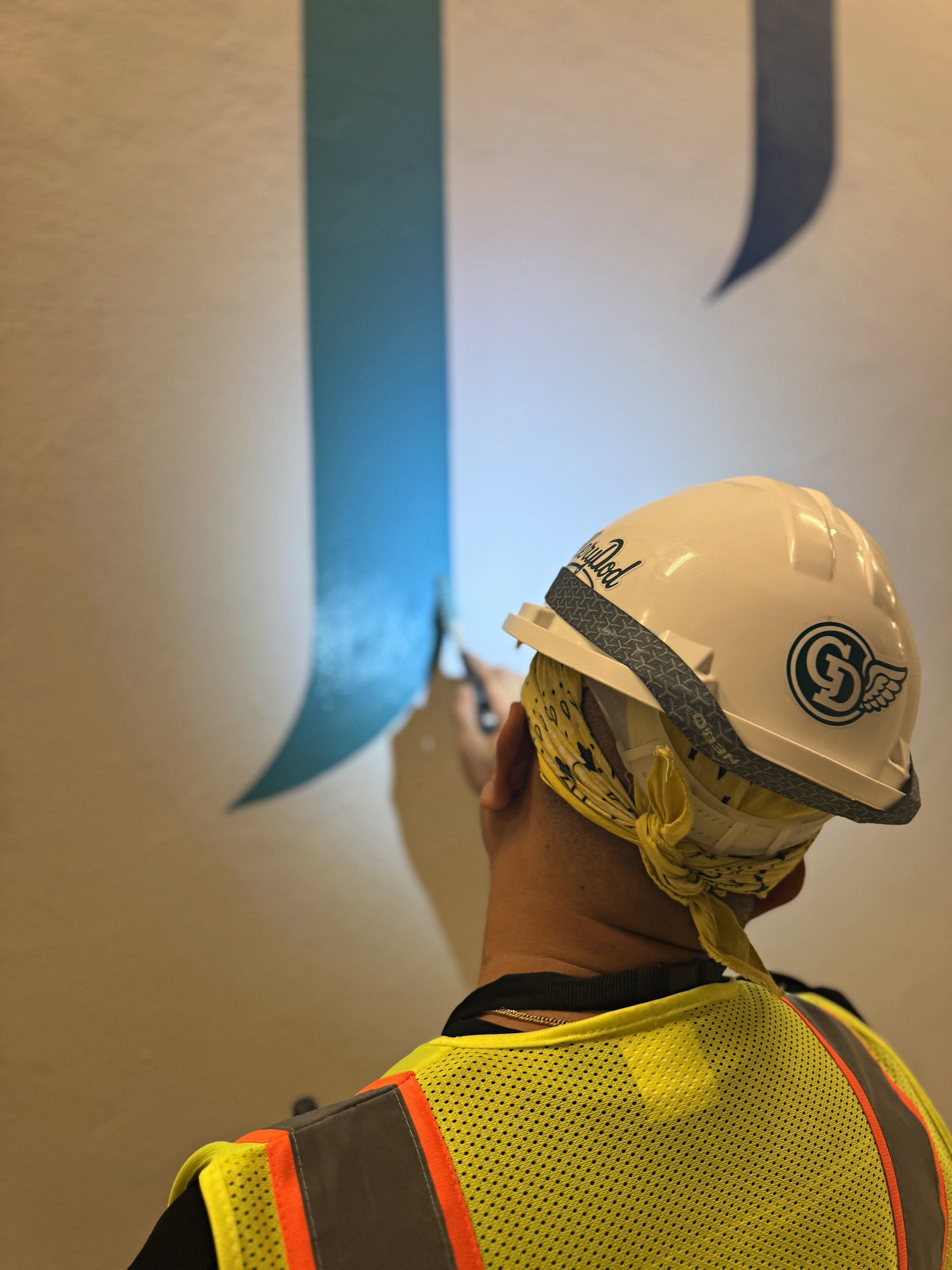 Gallery Dod branded safety helmet beside precise mural brushwork